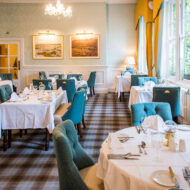 Elegant dining room with teal chairs, white tablecloths, and warm lighting at Old Ground Hotel.