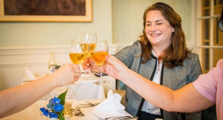 A group toasting with drinks at a bright, elegant hotel dining room, creating a warm atmosphere.