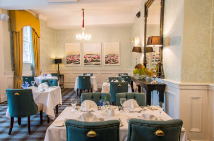 Elegant hotel dining room with cosy chairs and tables set for dinner.