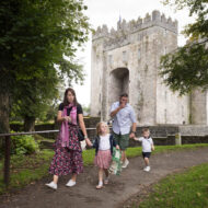 Family walking near historic castle surrounded by lush greenery at Old Ground Hotel.