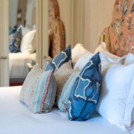 Elegant hotel room with a plush bed adorned with colourful, decorative pillows.