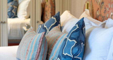 Elegant hotel room with a plush bed adorned with colourful, decorative pillows.