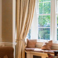 Sunlit window nook with elegant curtains and cosy seating in hotel lounge.