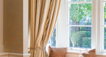 Sunlit window nook with elegant curtains and cosy seating in hotel lounge.