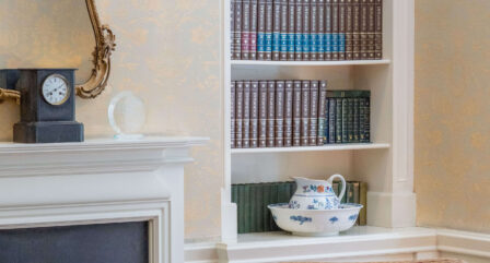 Cosy hotel lounge with elegant decor, featuring armchairs, a fireplace, and a bookshelf.