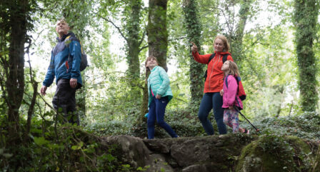 A family enjoys a nature walk in a lush, green woodland setting near Old Ground Hotel.
