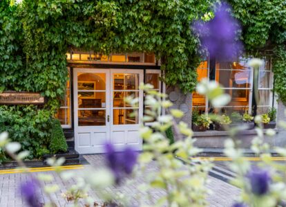 Ivy-covered entrance of Old Ground Hotel with inviting warm lights inside.
