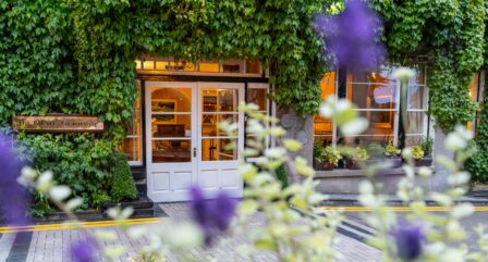 Ivy-covered entrance of Old Ground Hotel with inviting warm lights inside.
