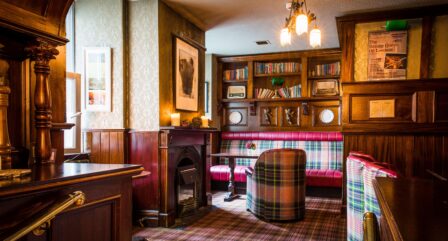 Cosy hotel lounge with plaid seating, warm lighting, and a fireplace, perfect for relaxing moments.
