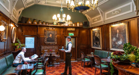 Cosy hotel lounge with historic decor, a family reading and enjoying drinks.