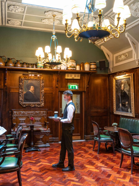 Cosy hotel lounge with historic decor, a family reading and enjoying drinks.