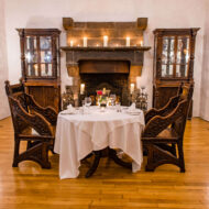 Cosy dining setup at Old Ground Hotel with a lit fireplace and elegant wooden chairs.