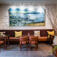 Cosy seating area with leather chairs, art, and decorative plants in an inviting hotel lounge.