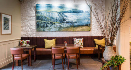 Cosy seating area with leather chairs, art, and decorative plants in an inviting hotel lounge.