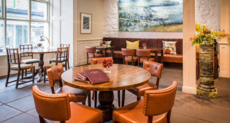 Warm hotel dining room with cosy seating, art, and soft lighting.