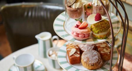 A tiered cake stand with colourful pastries and desserts set on a cosy cafe table.