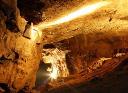 A warm-lit cave with a family exploring, surrounded by stunning rock formations.