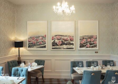 Elegant dining room with blue chairs, artwork, and a chandelier, set for family dinner.