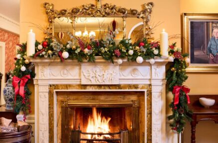 Cosy festive fireplace with garlands in hotel lounge, enhancing a warm welcoming atmosphere.
