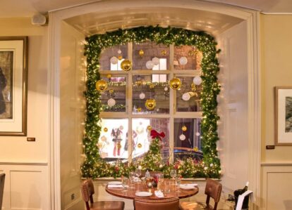 Cosy dining setup in a festively decorated hotel room with a window view.
