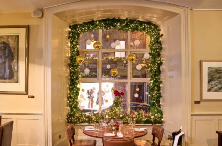 Cosy dining setup in a festively decorated hotel room with a window view.