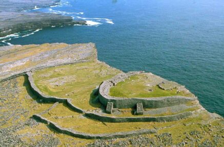 A family explores ancient stone ruins by the sea on a sunny day, enjoying scenic coastal views.