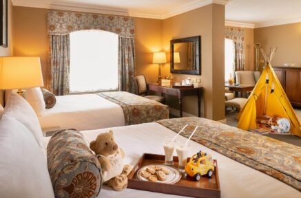 Cosy family hotel room with twin beds, toys, and a play tent, creating a welcoming atmosphere.