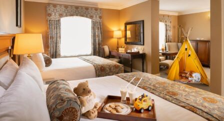Cosy family hotel room with twin beds, toys, and a play tent, creating a welcoming atmosphere.