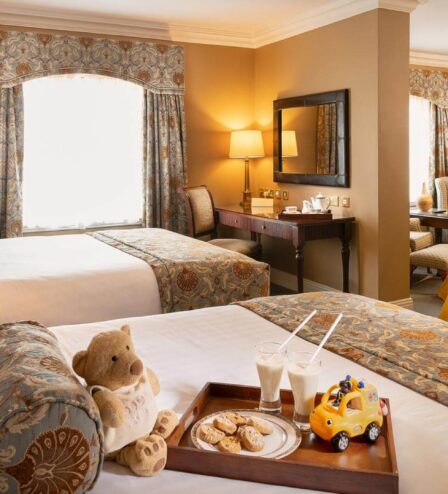 Cosy family hotel room with twin beds, toys, and a play tent, creating a welcoming atmosphere.
