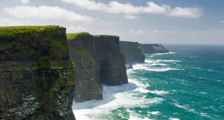 Stunning Cliffs of Moher with waves crashing below, under a bright sky, perfect for exploration.