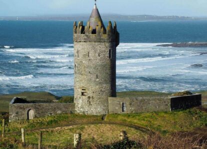 Historic tower overlooking scenic ocean waves on a sunny day.