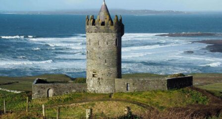 Historic tower overlooking scenic ocean waves on a sunny day.
