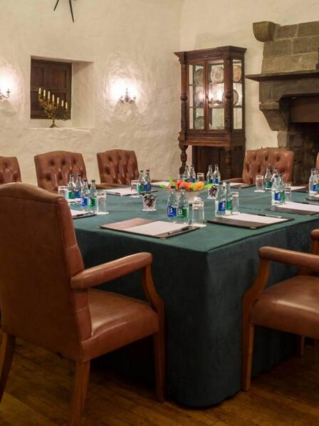 Cosy meeting room with elegant leather chairs around a table, warm lighting and a fireplace.