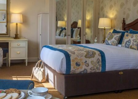 Elegant hotel room with a double bed, cosy seating, and afternoon tea setup.
