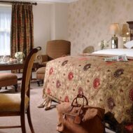 Elegant hotel room with a plush bed, cosy chairs, and inviting decor for a relaxing stay.