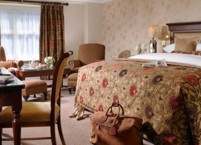 Elegant hotel room with a plush bed, cosy chairs, and inviting decor for a relaxing stay.