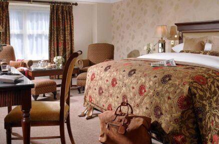 Elegant hotel room with a plush bed, cosy chairs, and inviting decor for a relaxing stay.
