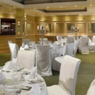 Elegant dining room in Old Ground Hotel set for a family event with white tablecloths and candelabras.