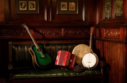 Warm, wooden lounge with guitar, banjo, and accordion on a green leather sofa at Old Ground Hotel.