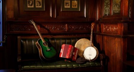 Warm, wooden lounge with guitar, banjo, and accordion on a green leather sofa at Old Ground Hotel.