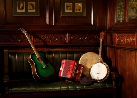 Warm, wooden lounge with guitar, banjo, and accordion on a green leather sofa at Old Ground Hotel.