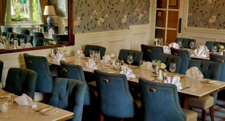 Elegant dining room in a hotel with set tables and blue chairs, ready for guests.