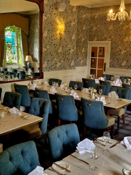 Elegant dining room in a hotel with set tables and blue chairs, ready for guests.