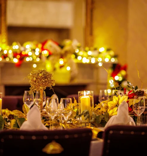 Cosy dining room with candlelit table, festive decorations, and glowing lights.